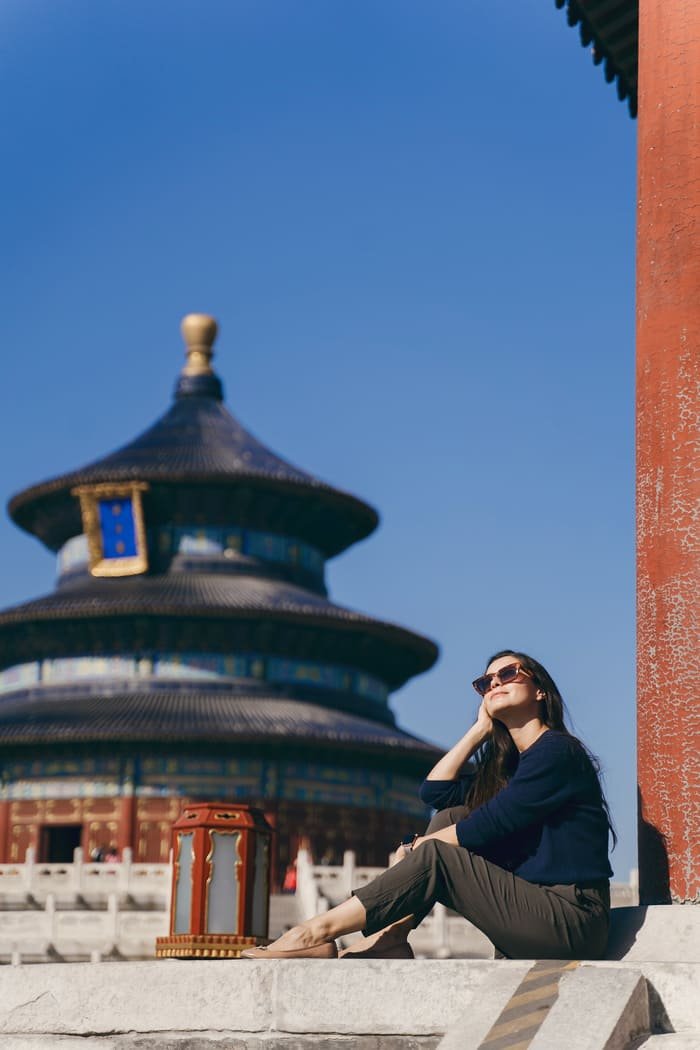 Foto de mujer posando y templo chino a lo lejos